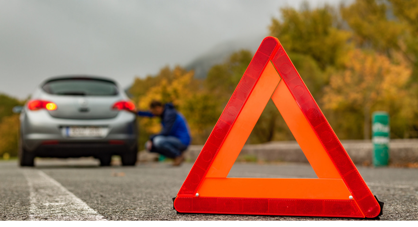 SUN Motors roadside assistance — warning triangle beside a vehicle on an autumn road